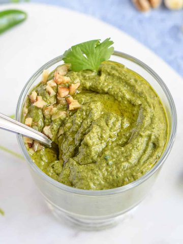 poblano pesto shown with a spoon in a glass jar