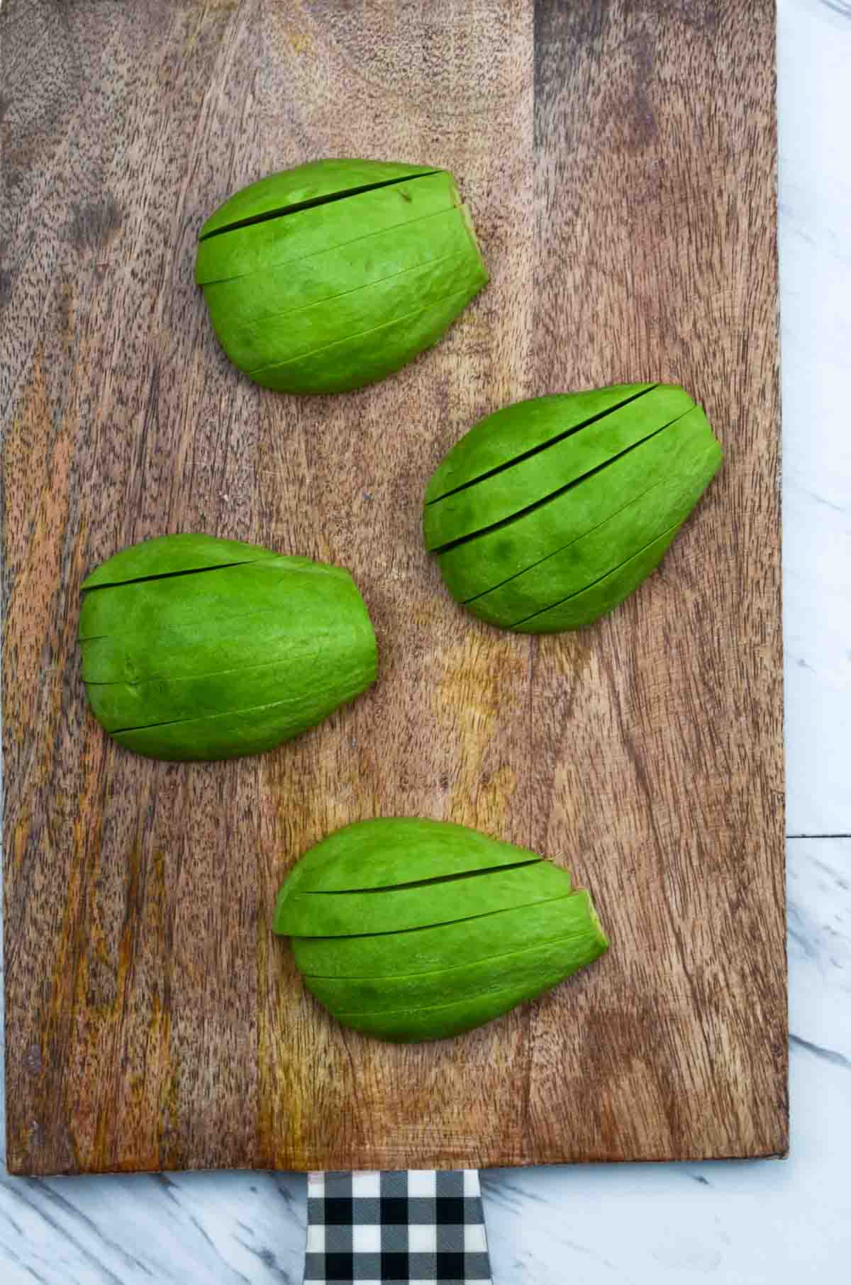 Peeled and cut avocados sliced on the wooden board.