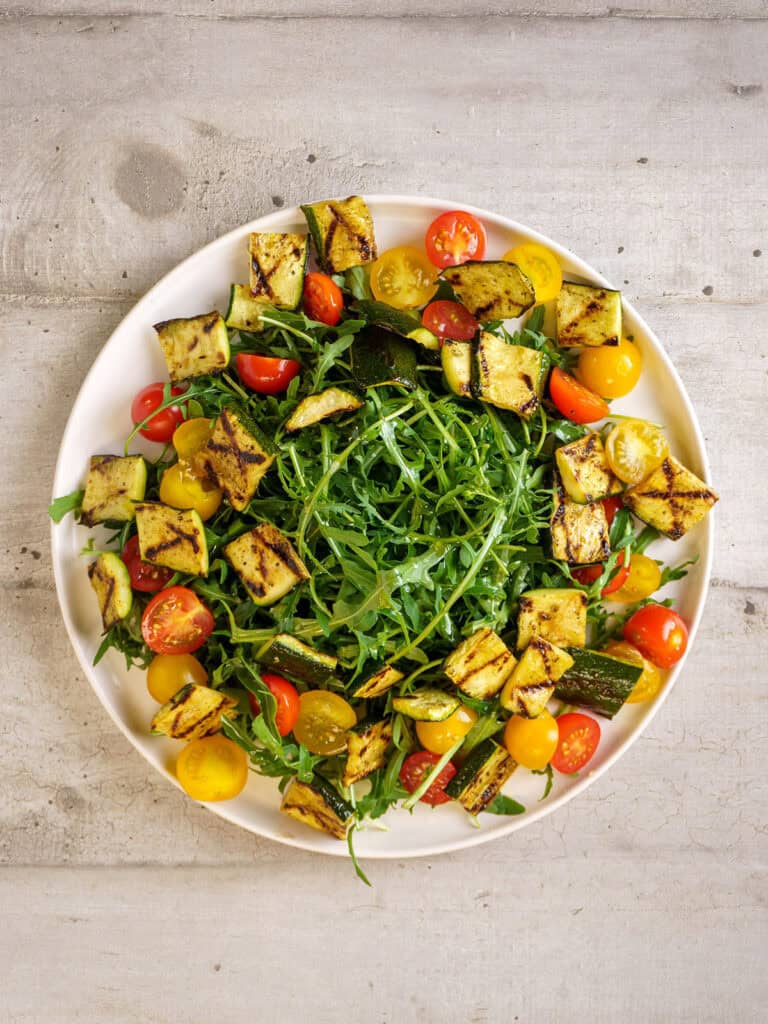 Same salad base with burrata added on top, centered over the greens, zucchini, and tomatoes—ready for final garnishes.